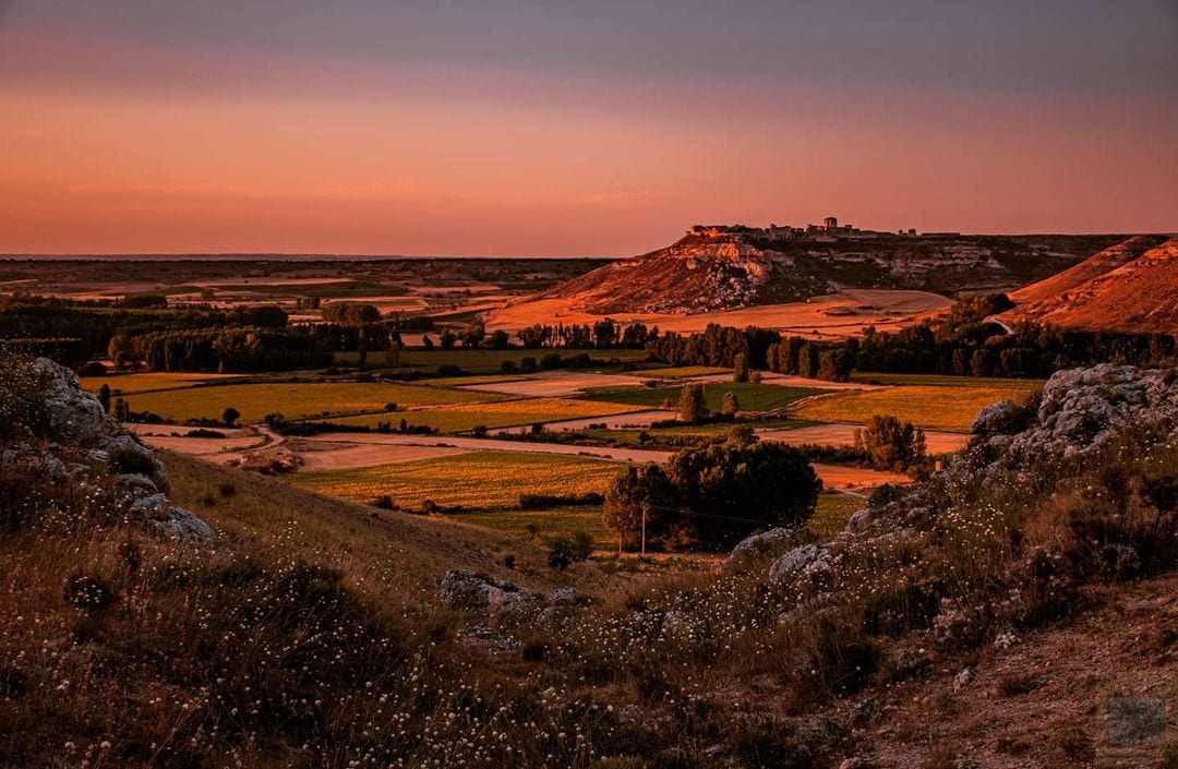Atardecer sobre el valle, con campos y un pueblo en lo alto del páramo